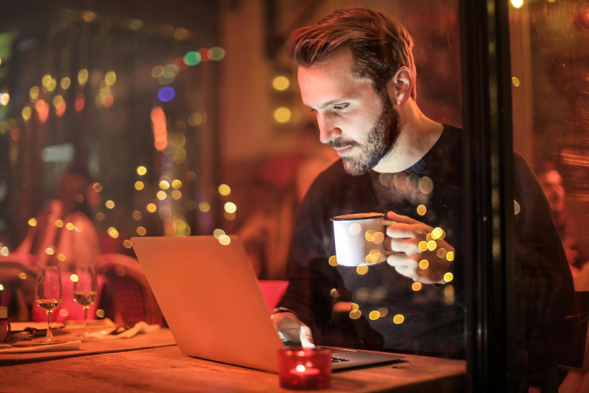 A man, sitting in front of a computer with a coffee in his hand - pexels-olly-842548