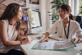 Two people, woman in modern travel agency talking with a female travel agent, she is planning a vacation.